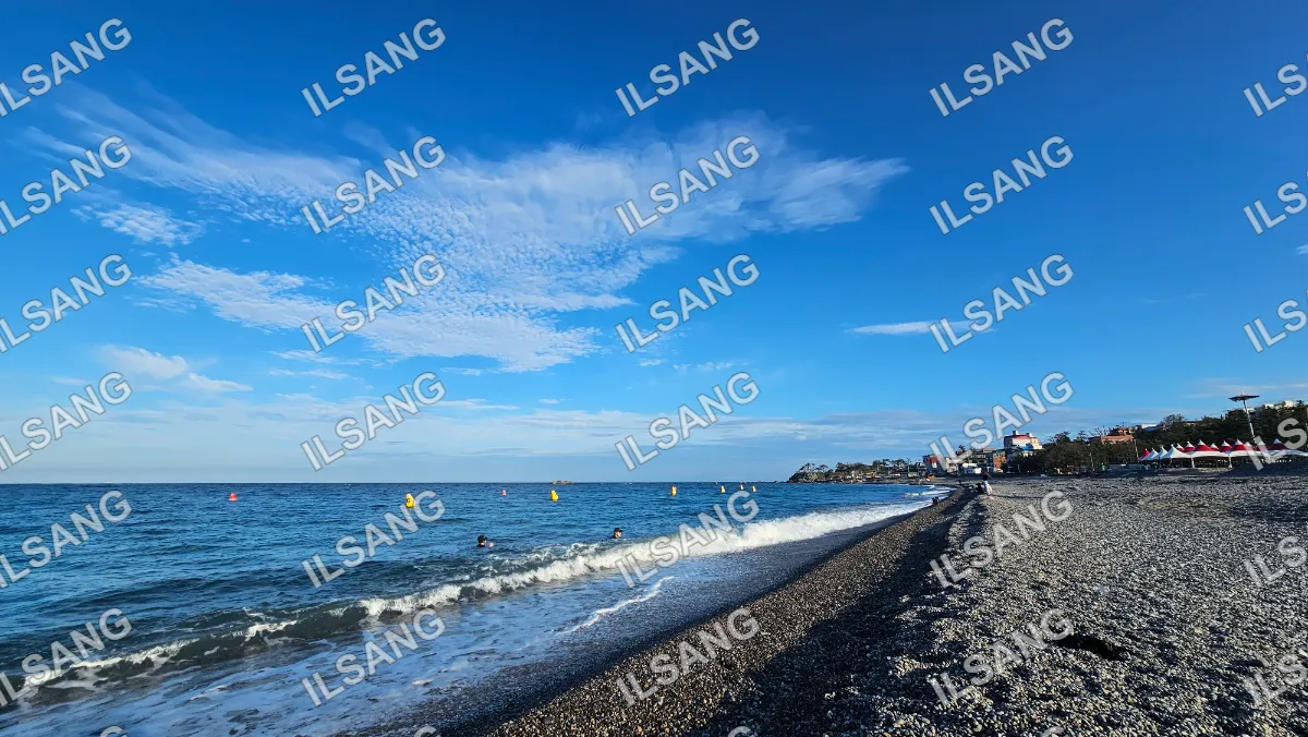 A beach scene with a few people and a boat in the water.
