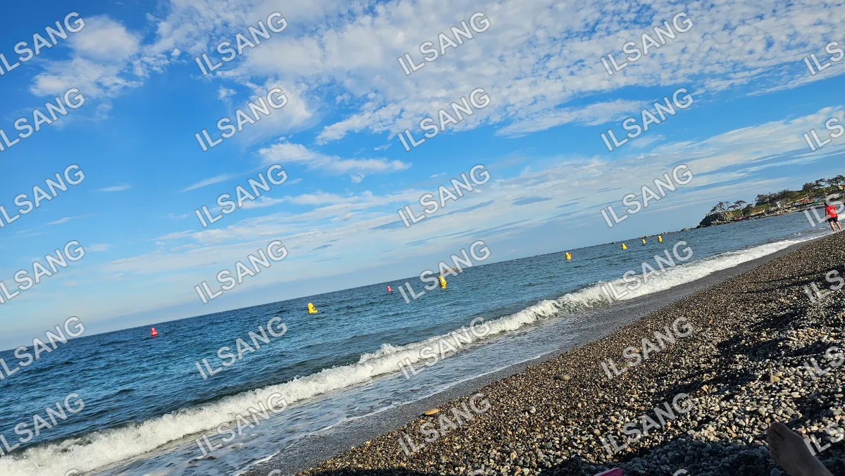 A beach scene with a person standing on the sand and a boat in the water.