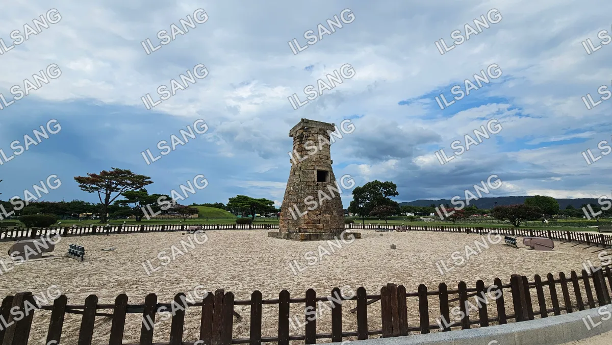 A brick tower stands in a sandy area.