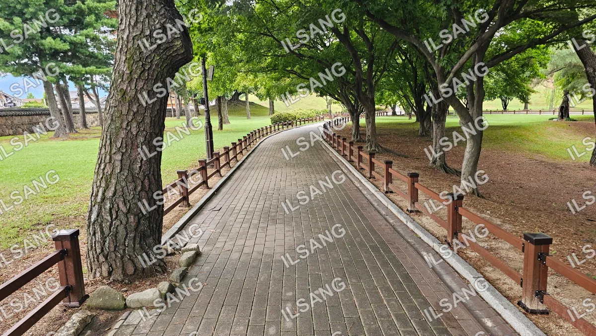 A brick walkway in a park with trees on both sides.