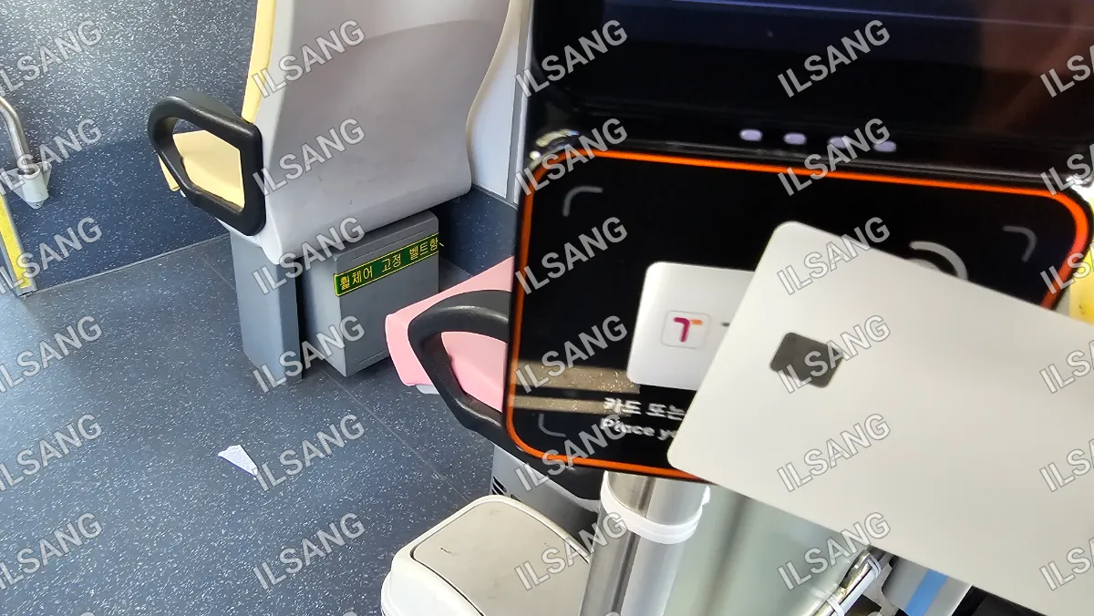 A cell phone is attached to a pink seat on a bus.