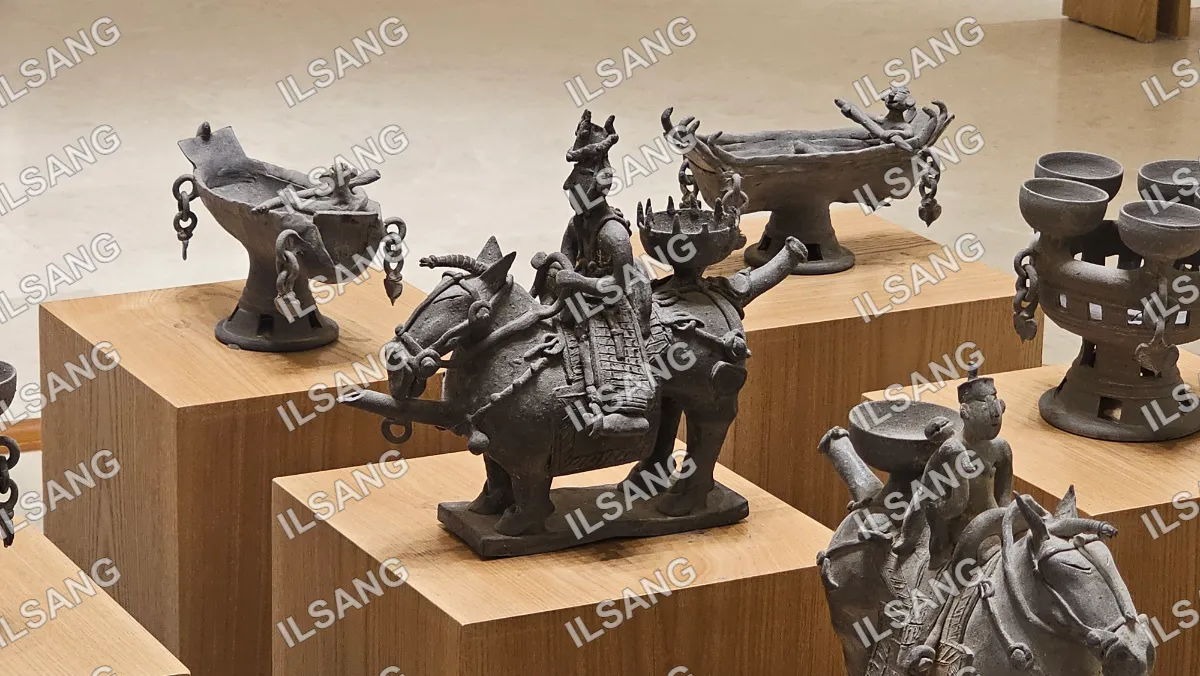 A collection of ancient statues, including a horse and a man, are displayed on a wooden shelf.