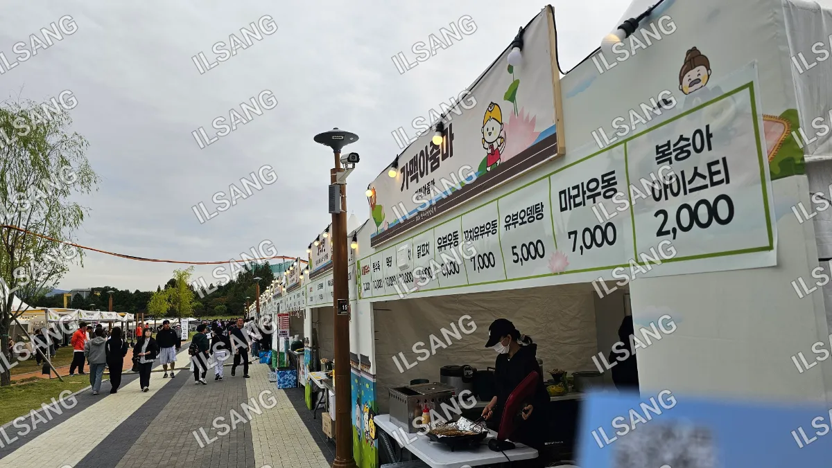 A food stand with a woman cooking in front of it.