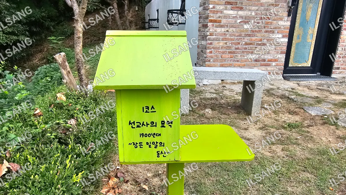 A green box with a yellow top that has a sign on it.