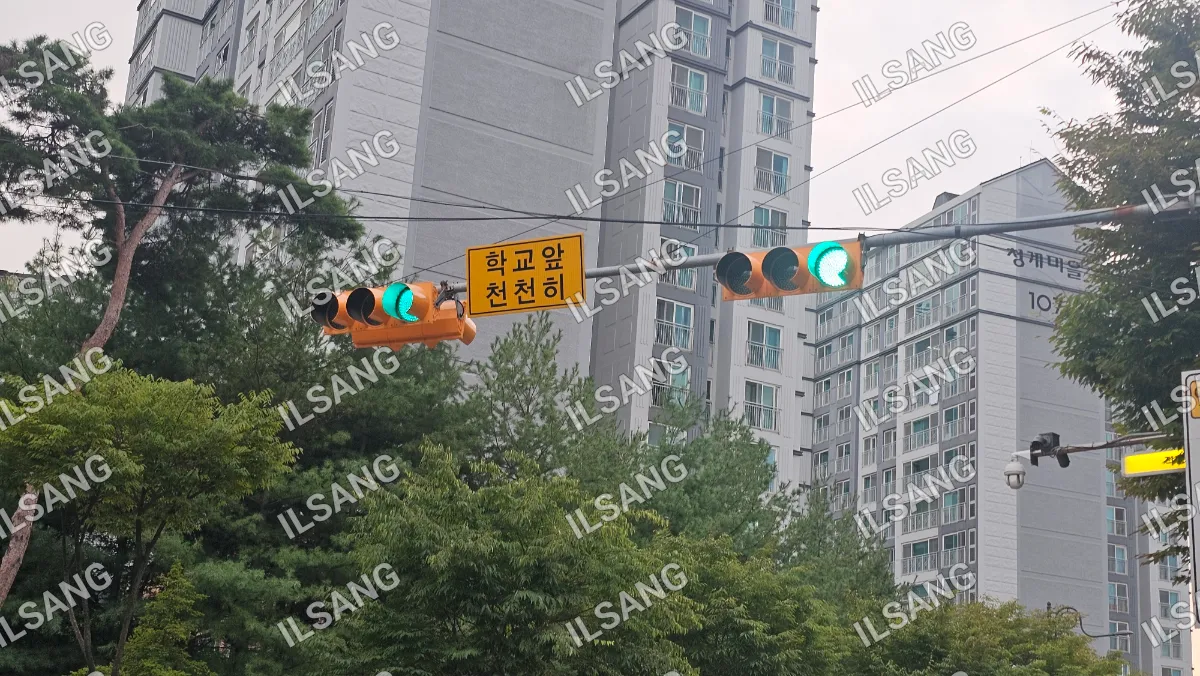 A green traffic light is hanging from a wire above a street.