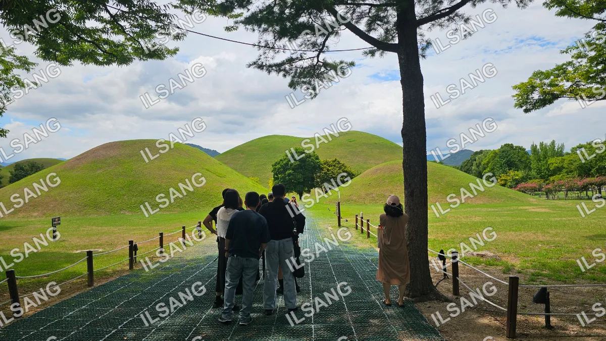 A group of people standing on a path in front of a hill.