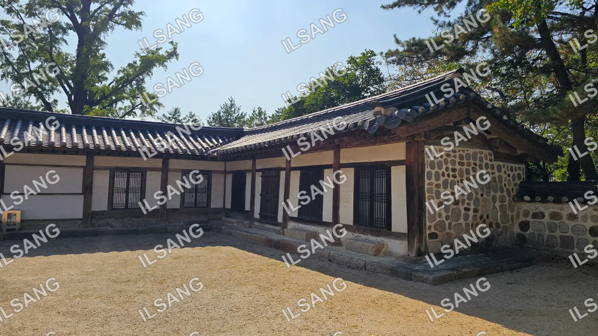 A house with a shingled roof and a stone wall.
