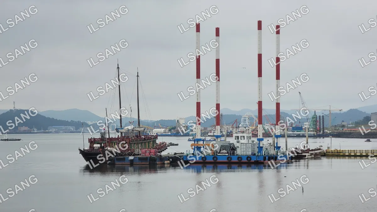 A large boat is docked in a harbor with other boats in the background.