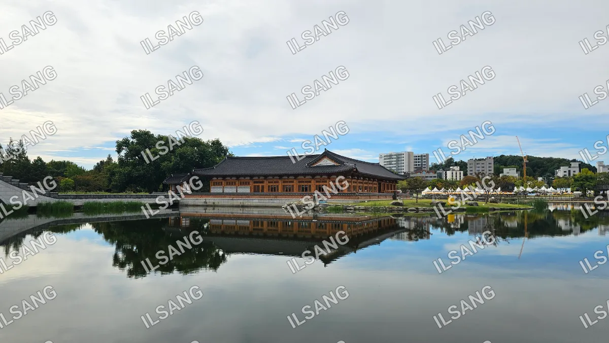 A large building with a pagoda roof is reflected in a lake.