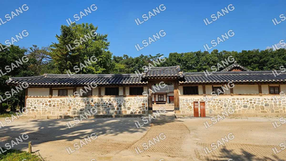 A large building with a stone wall and a wooden door.