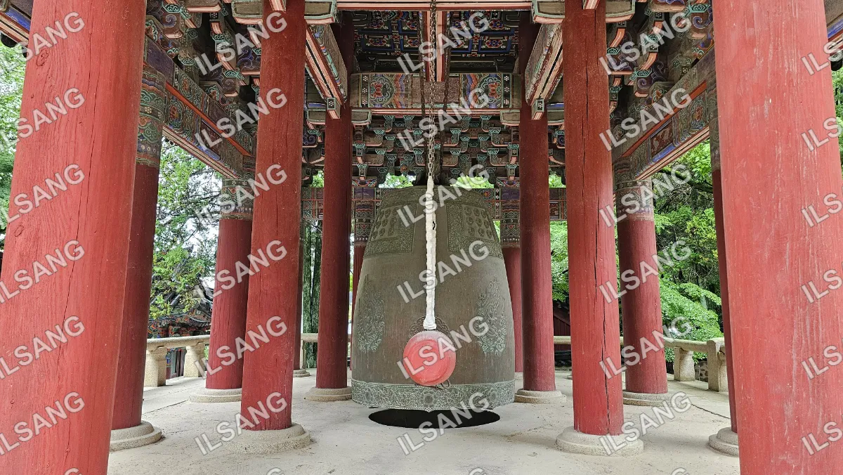 A large red and gold bell hangs from a red structure.