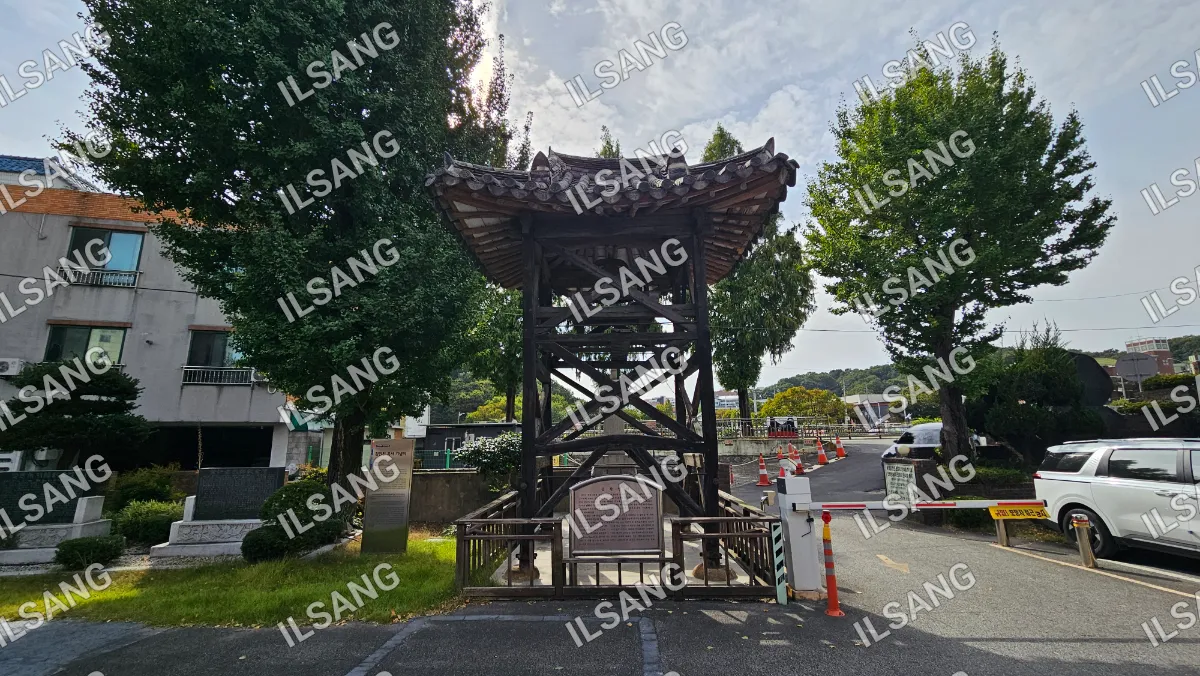 A large wooden structure with a roof and a sign on the side of the road.