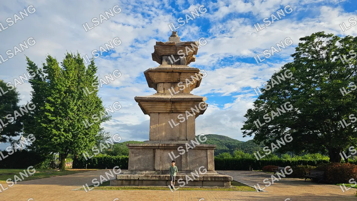 A man stands in front of a large stone monument.
