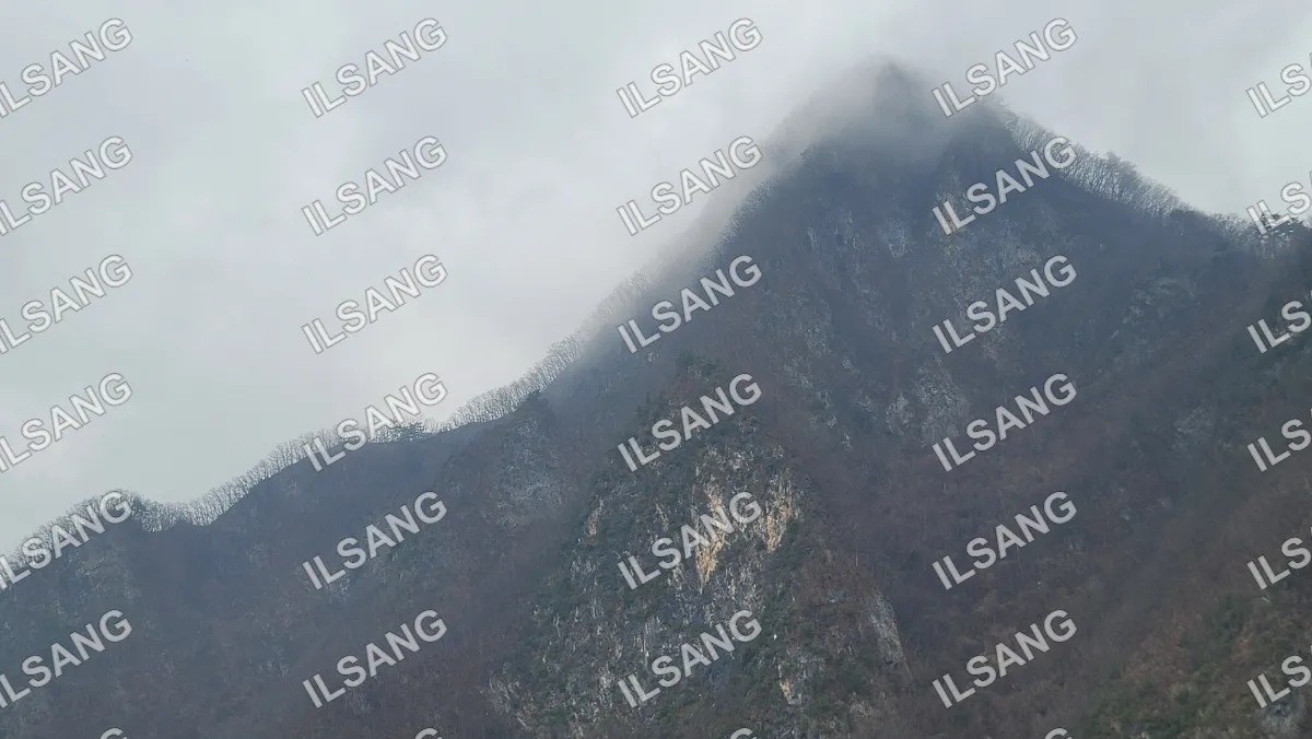 A mountain with a cloudy sky above it.