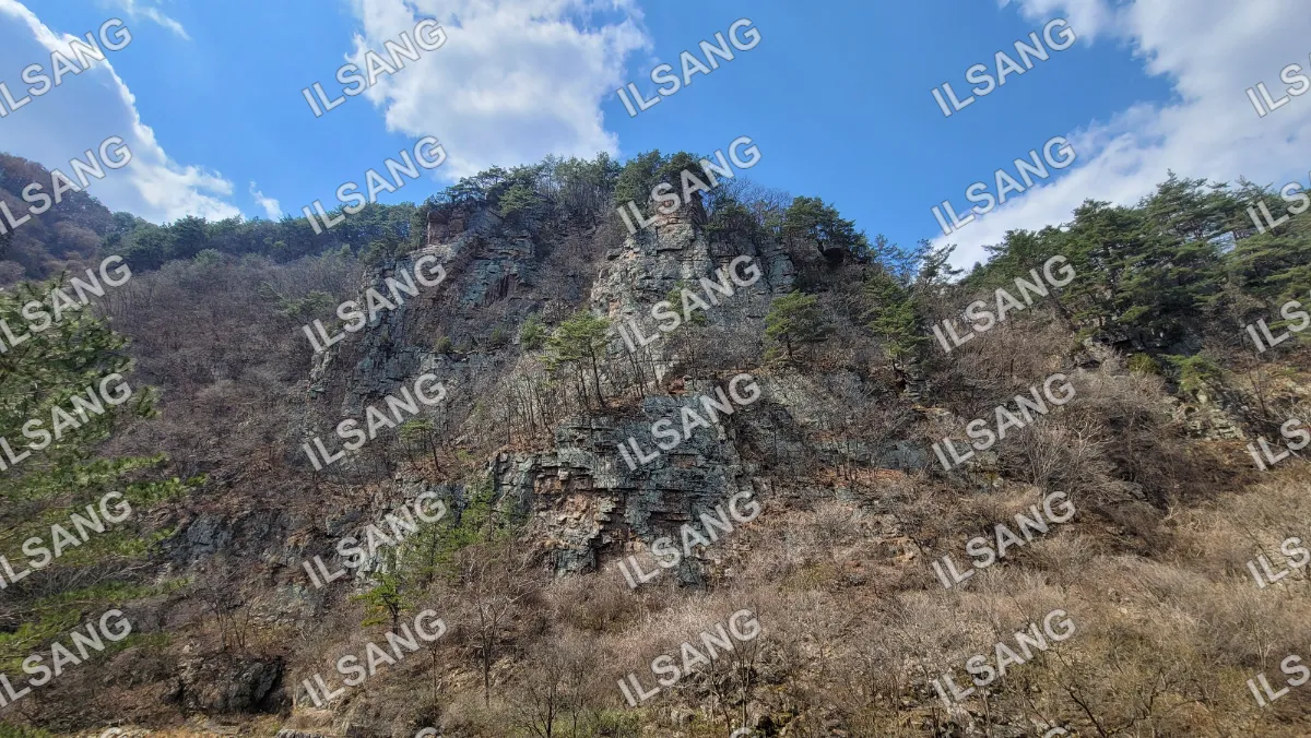 A mountain with a rocky cliff and a blue sky.