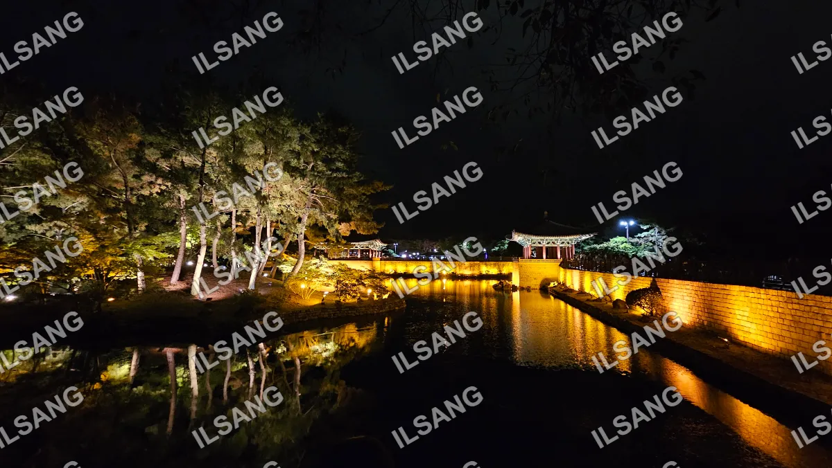 A nighttime scene of a lake with a bridge and a building in the background.