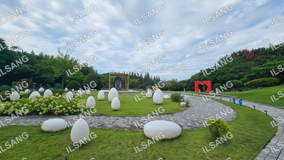 A park with a pathway and white rocks and eggs.