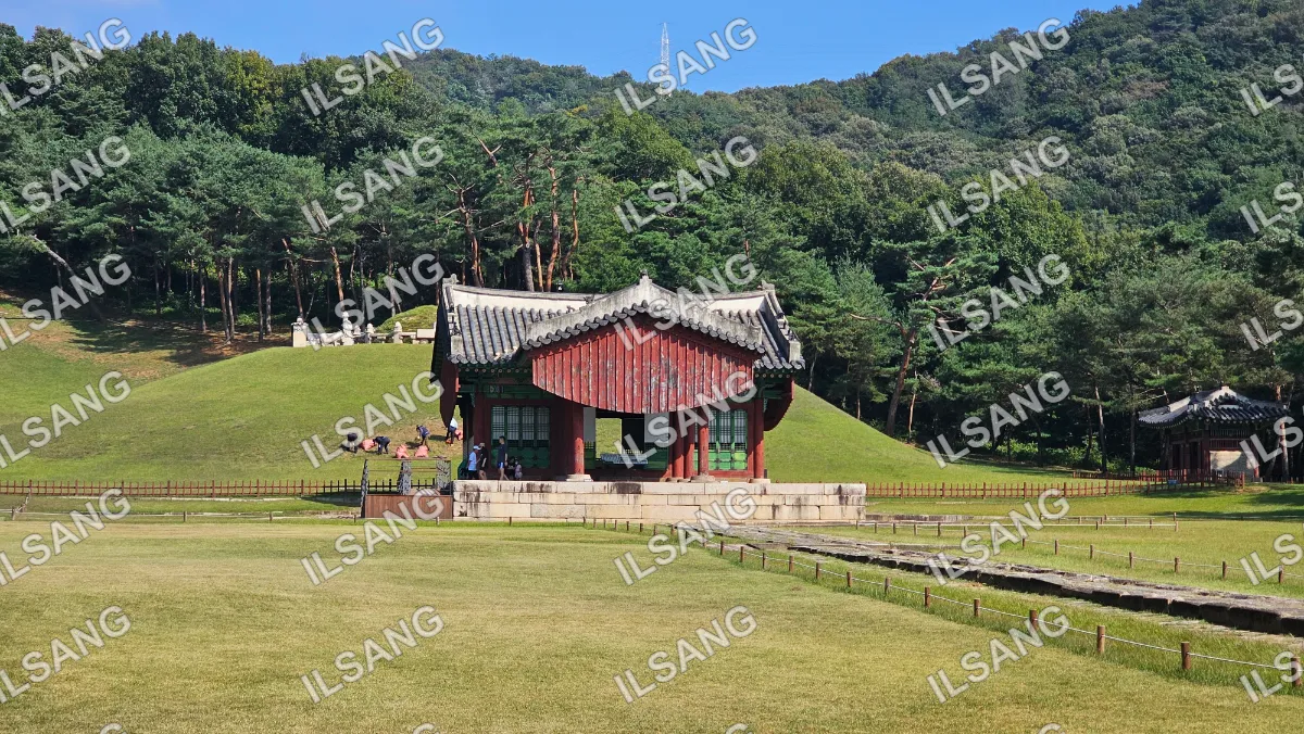 A red and white building with a green roof is surrounded by a grassy area.