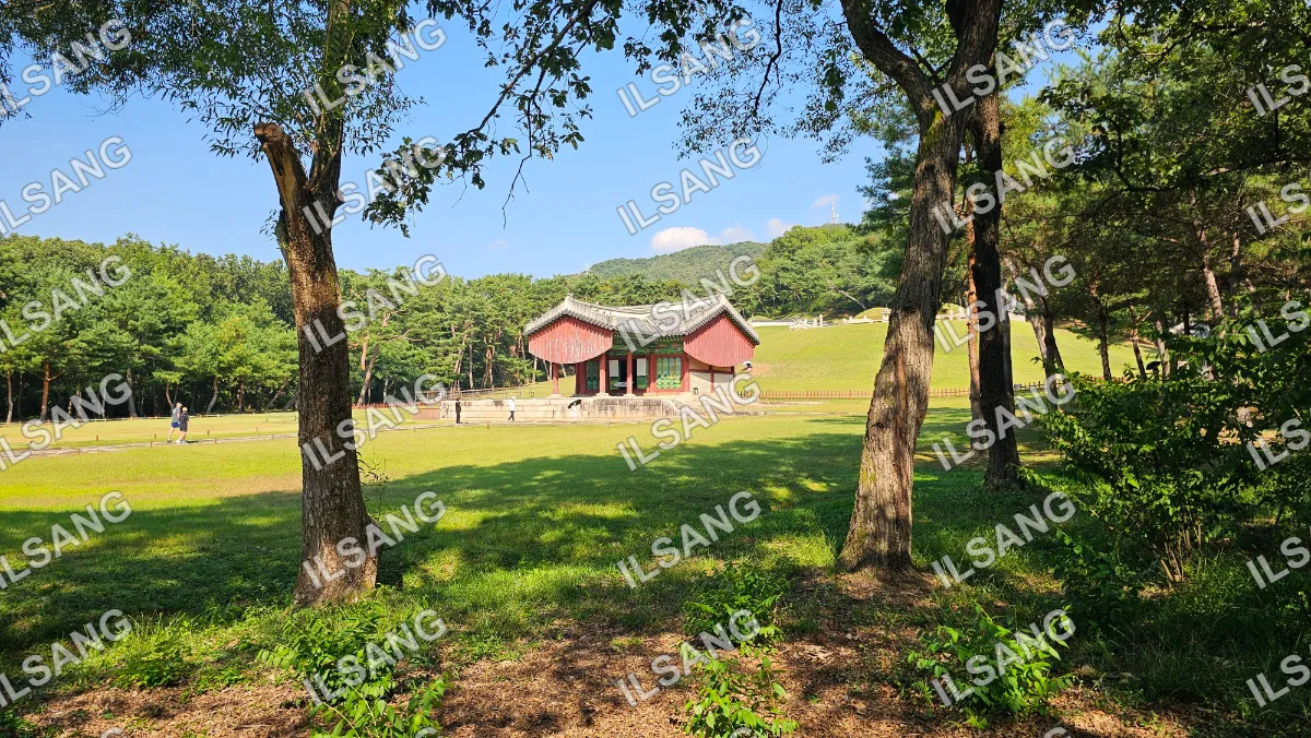 A red building with a white roof is surrounded by trees.