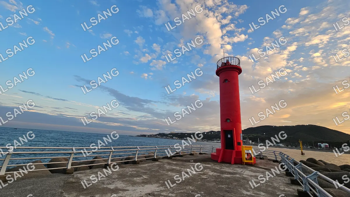 A red lighthouse with a yellow top is on a pier.