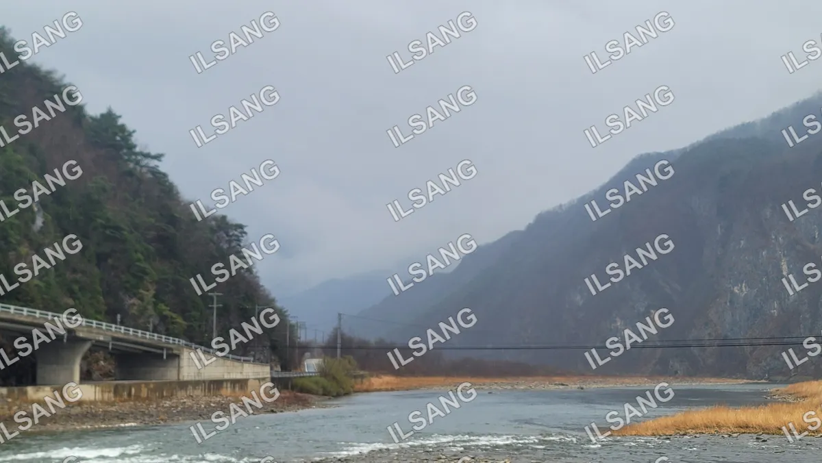 A river with a bridge and a mountain in the background.