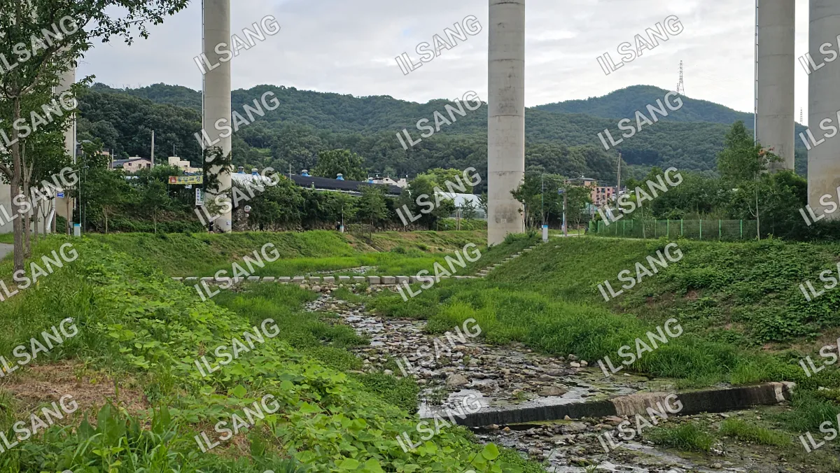 A river with a concrete wall and a bridge over it.