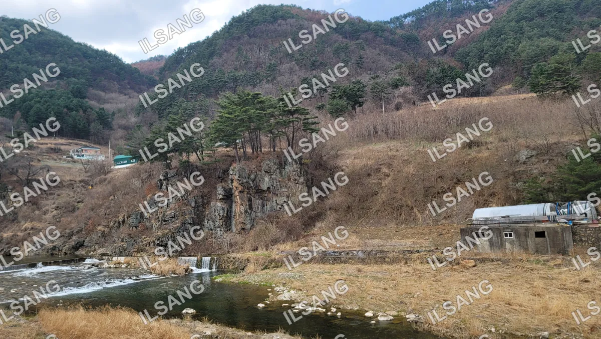 A river with a waterfall and a mountain in the background.
