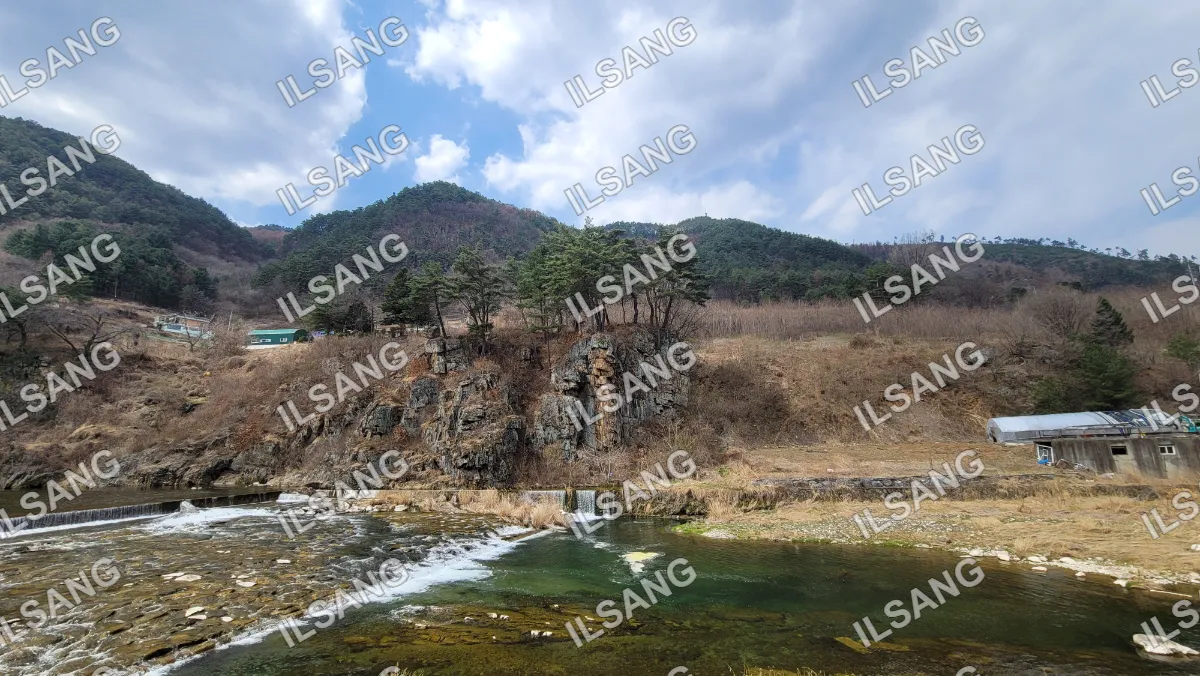 A river with a waterfall and a mountain in the background.