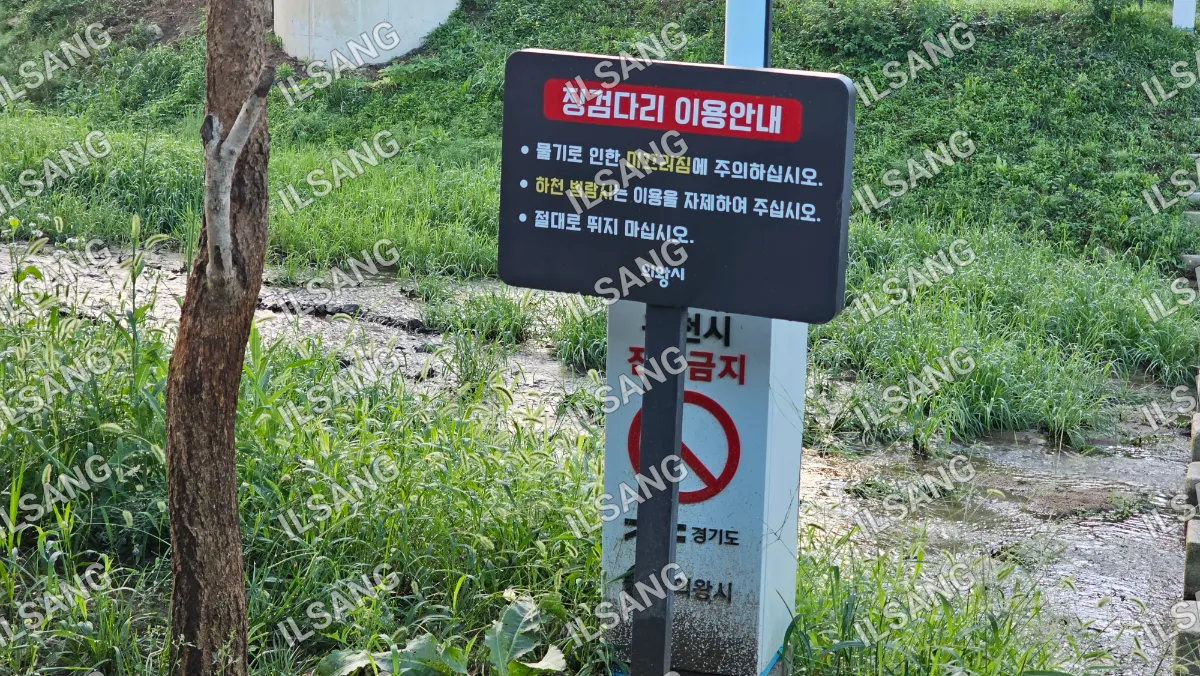 A sign in a foreign language is posted in a grassy area.