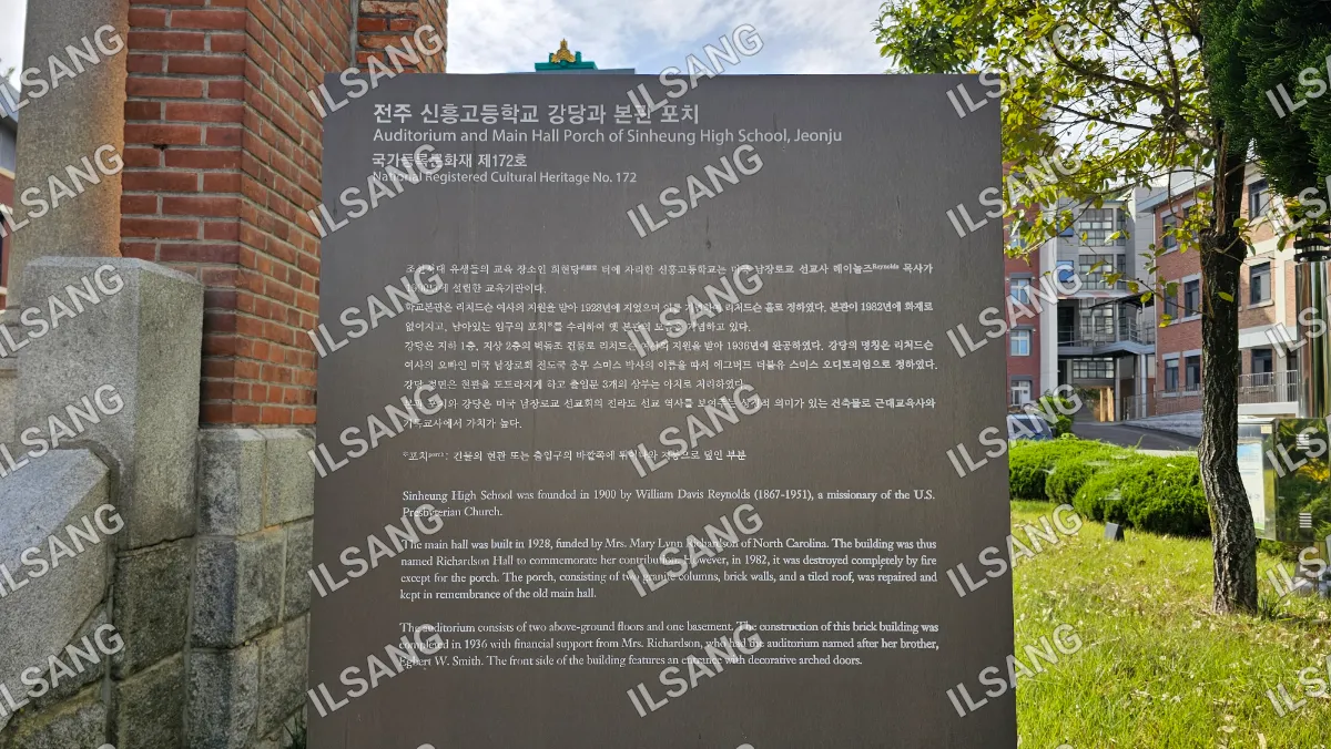 A sign in a foreign language is posted on a brick wall.