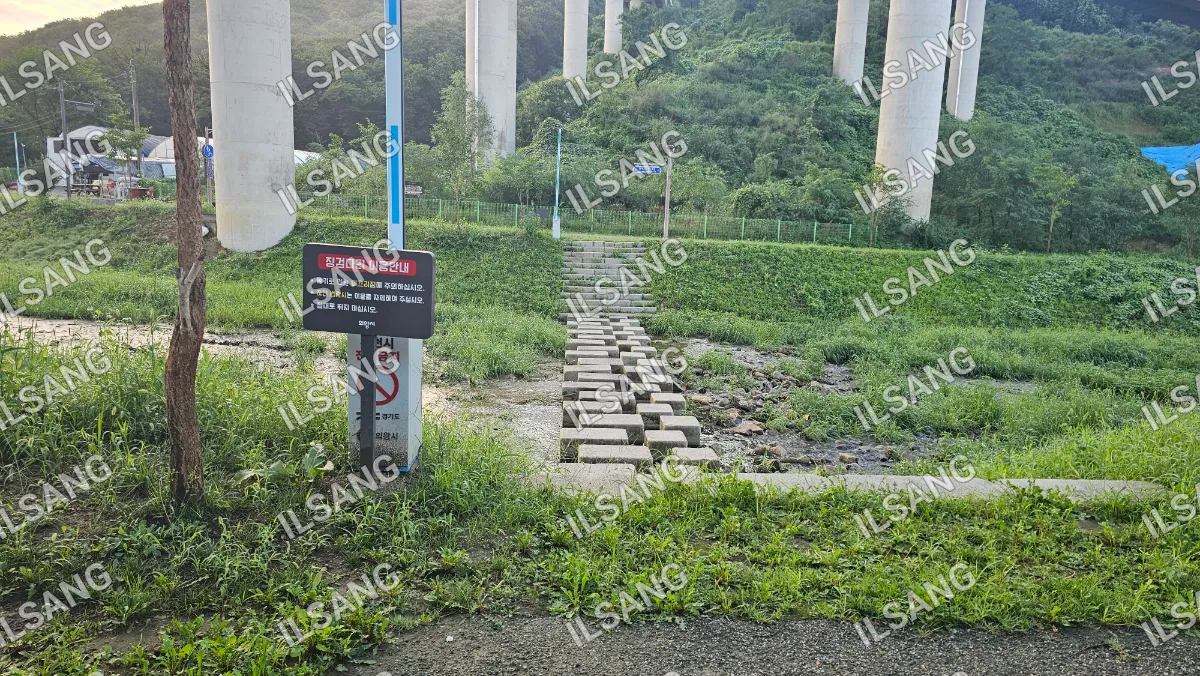 A sign is on a pole in front of a concrete staircase.