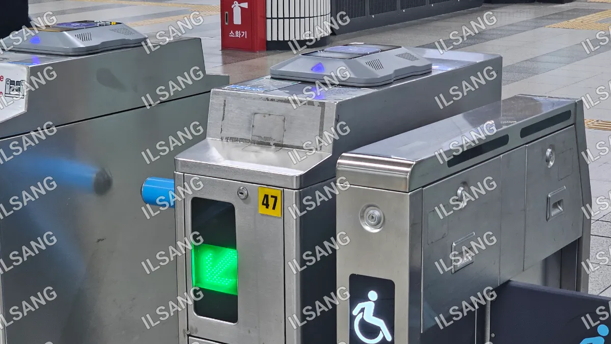 A silver and black subway machine with a green light on the bottom.