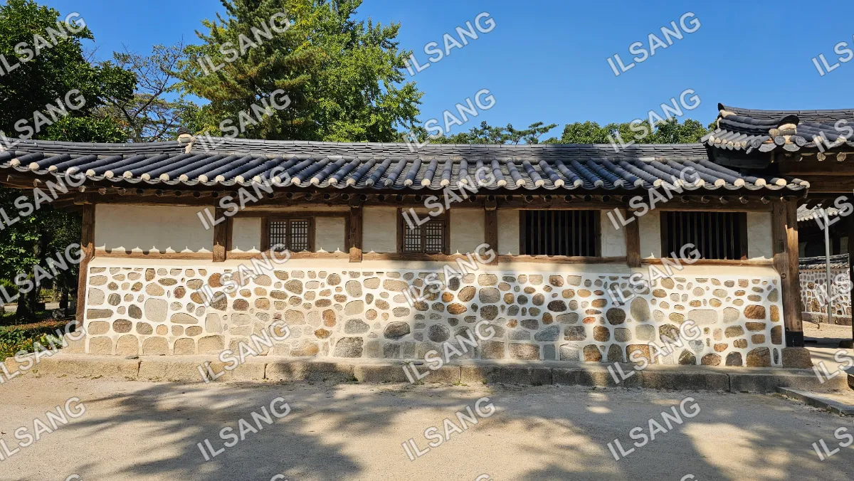 A small building with a stone wall and a wooden roof.