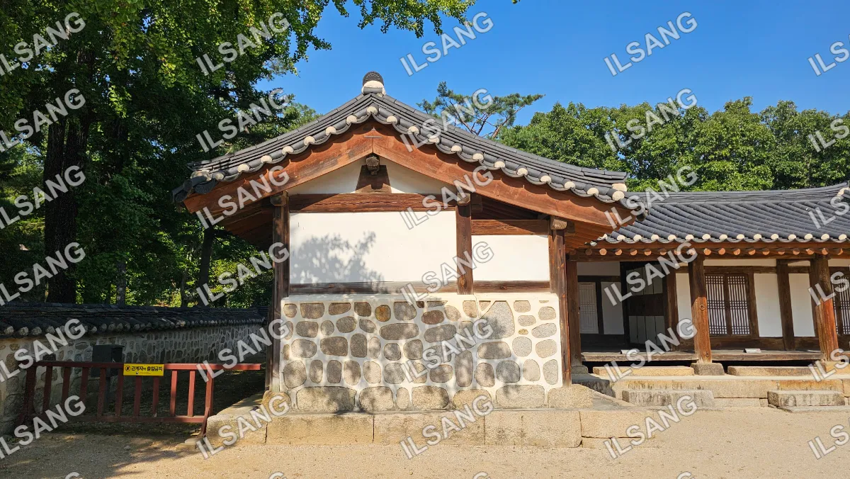A small building with a tile roof and a stone wall.
