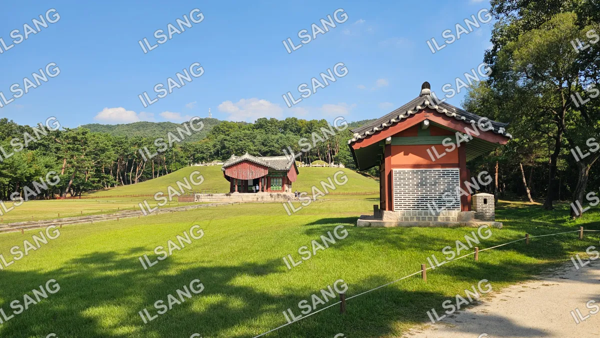 A small red building with a black roof is located in a park.