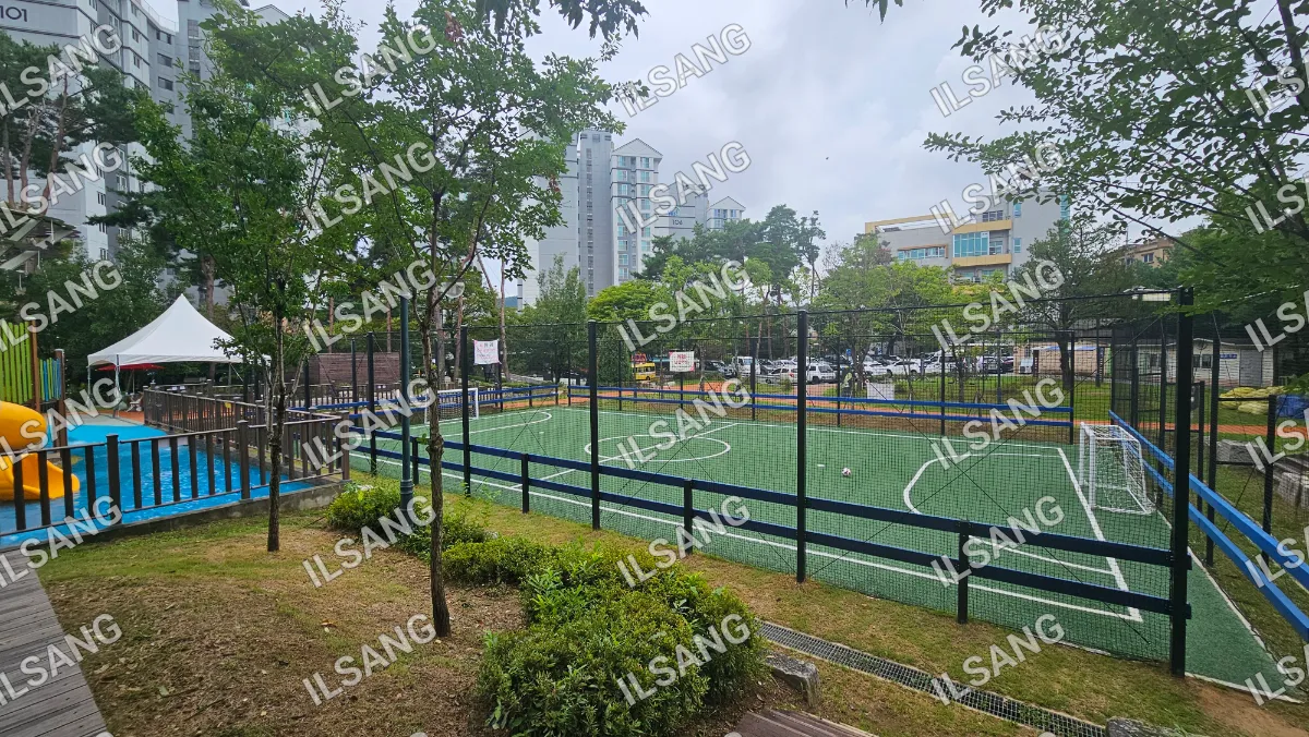 A soccer field with a fence and a tree in the foreground.