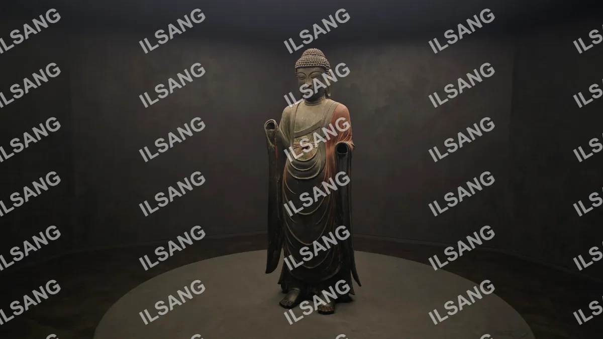 A statue of a person with a hooded robe is sitting on a pedestal.