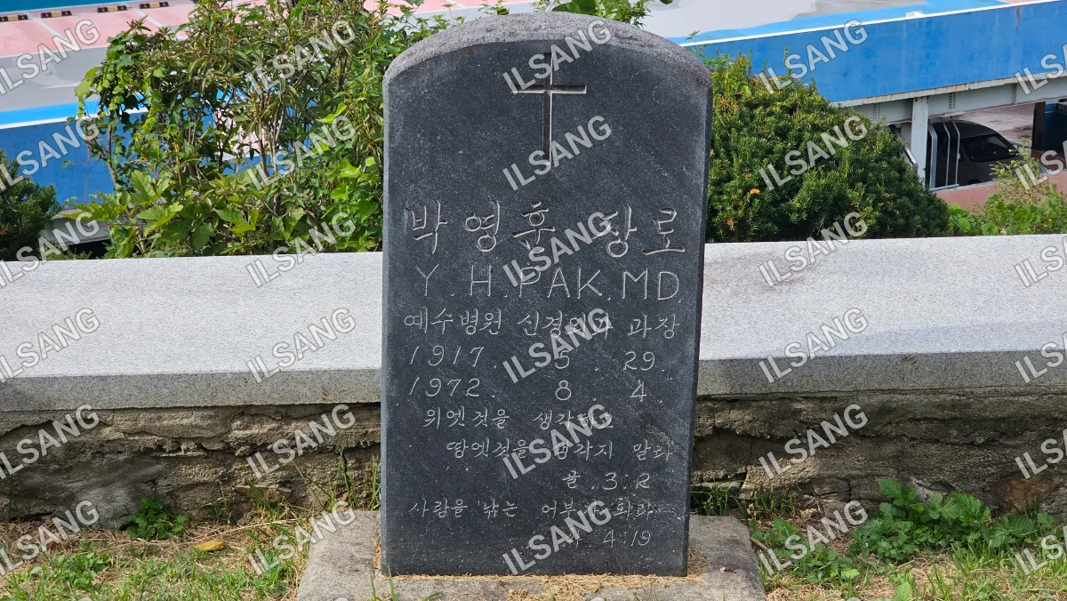 A stone monument with a cross on top and the name Hyukak MD.