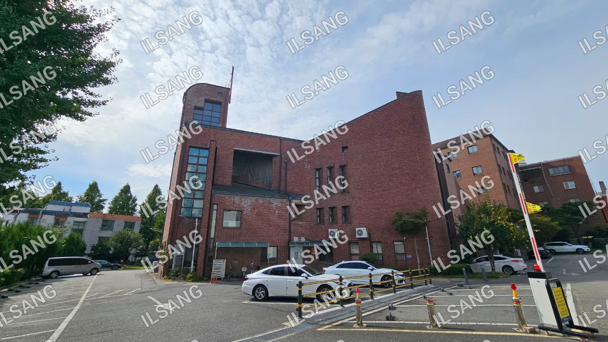 A white car is parked in front of a brick building.