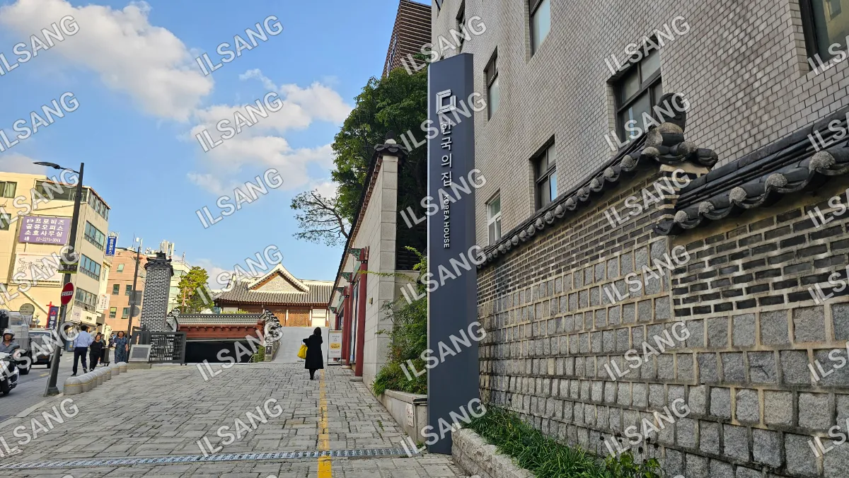 A woman walking down a street in front of a building with a sign on it.