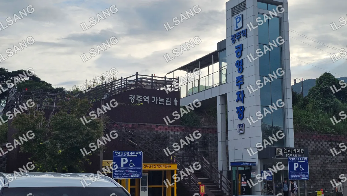 A yellow building with a blue sign and a parking lot.