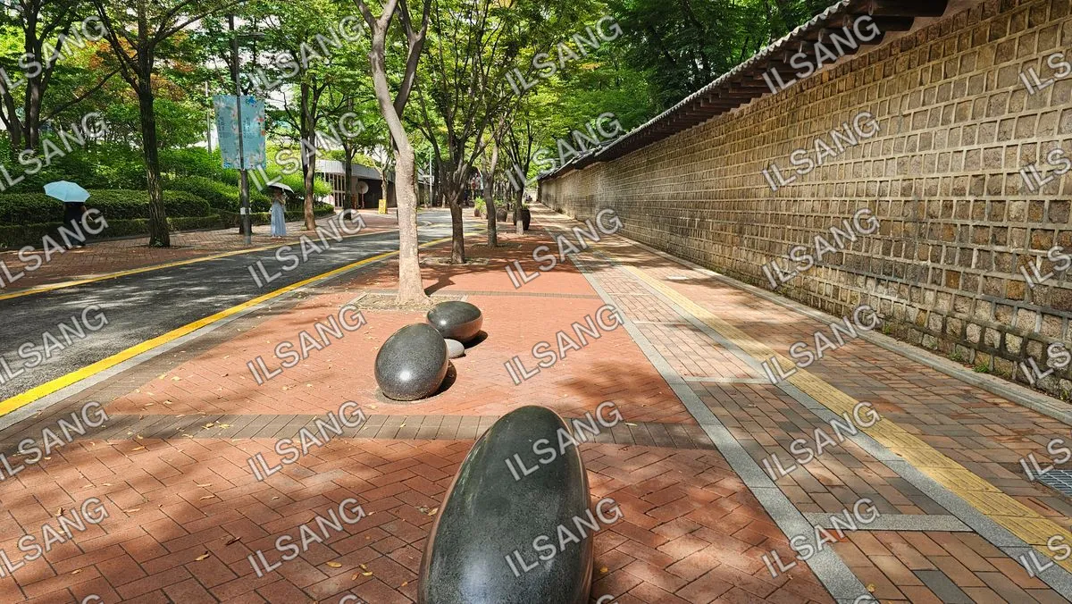 Two large black rocks on a brick walkway.