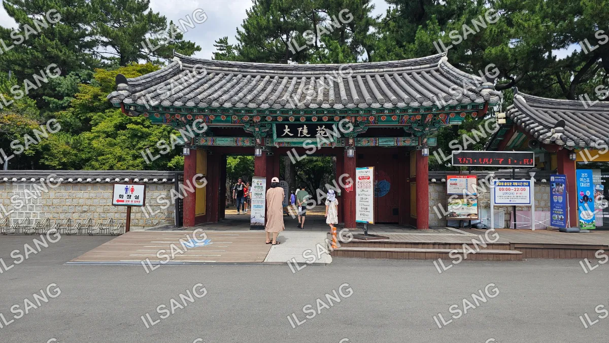 People walking through a gate in front of a building with a red roof.