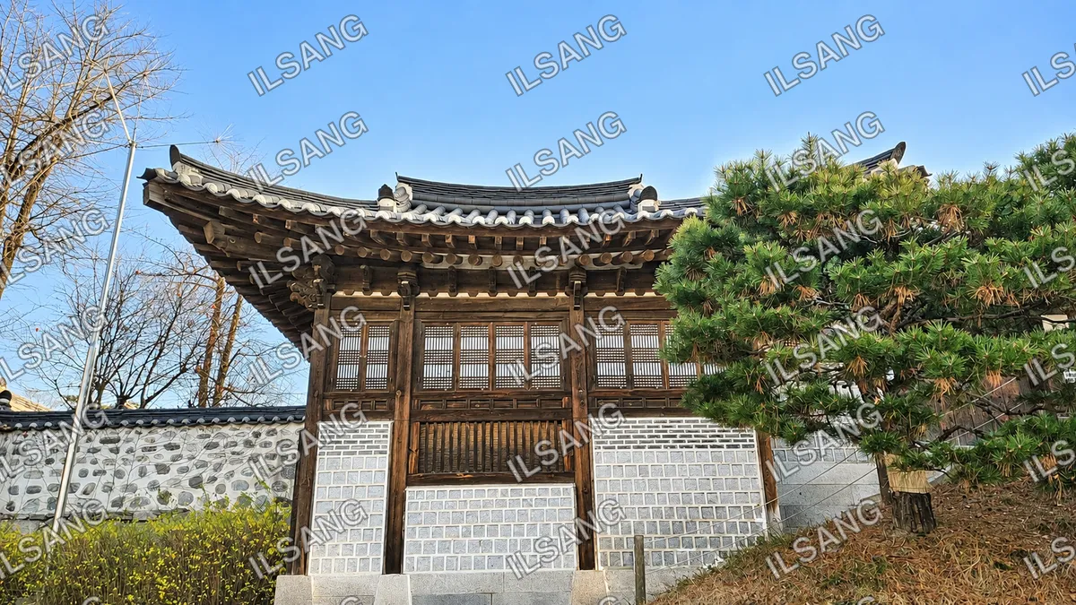A white building with a roof and a tree in front of it.