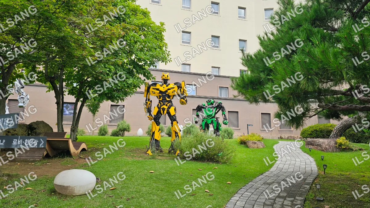 Two robot statues are standing in a grassy area.