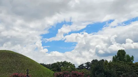 A beautiful blue sky with clouds and a green hillside