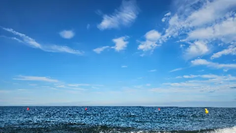 A blue sky with clouds and a red buoy in