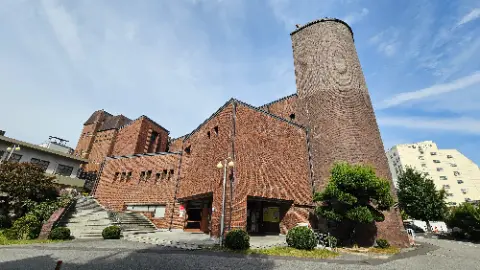 A brick building with a tall tower and a sign
