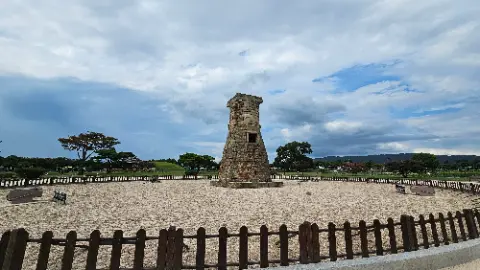 A brick tower stands in a sandy area