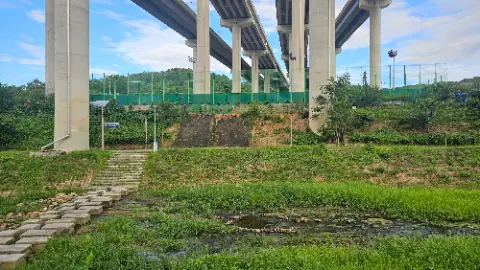 A bridge over a river with a green field and